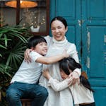 Photo of Woman Hugging Her Children While Smiling